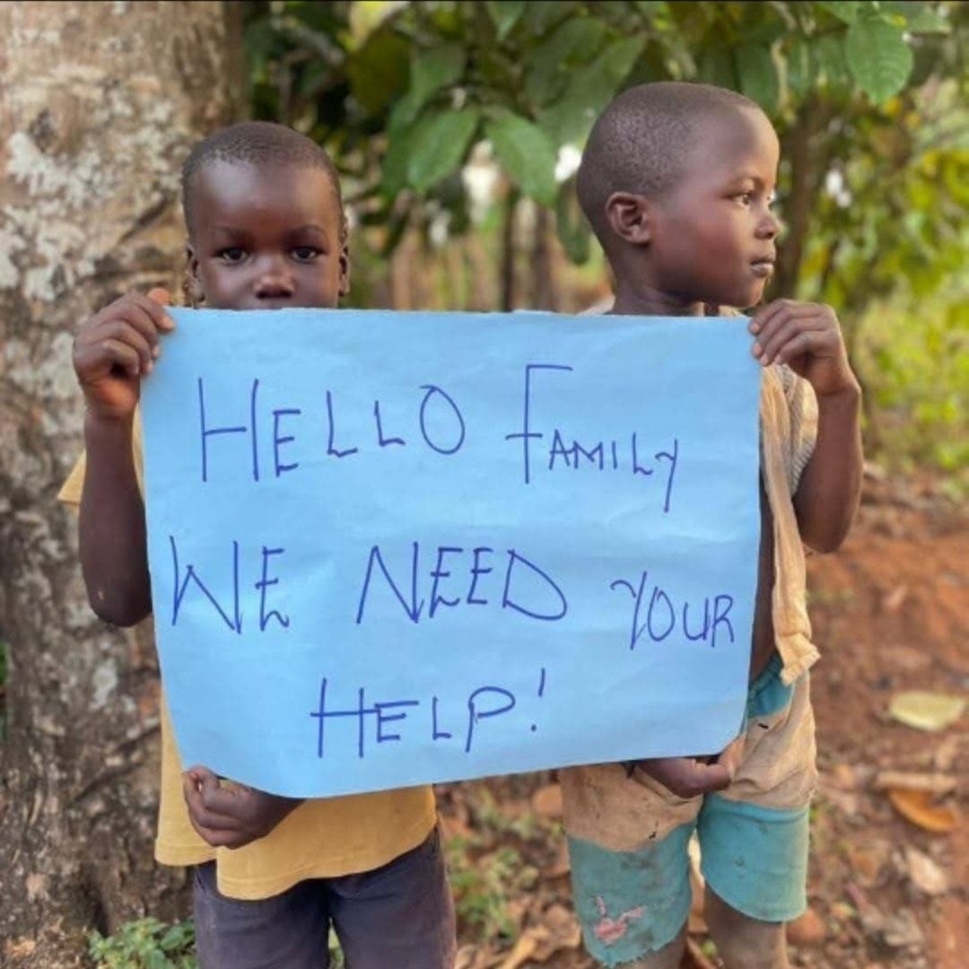 Two children holding a sign that reads: Hello family, we need your help