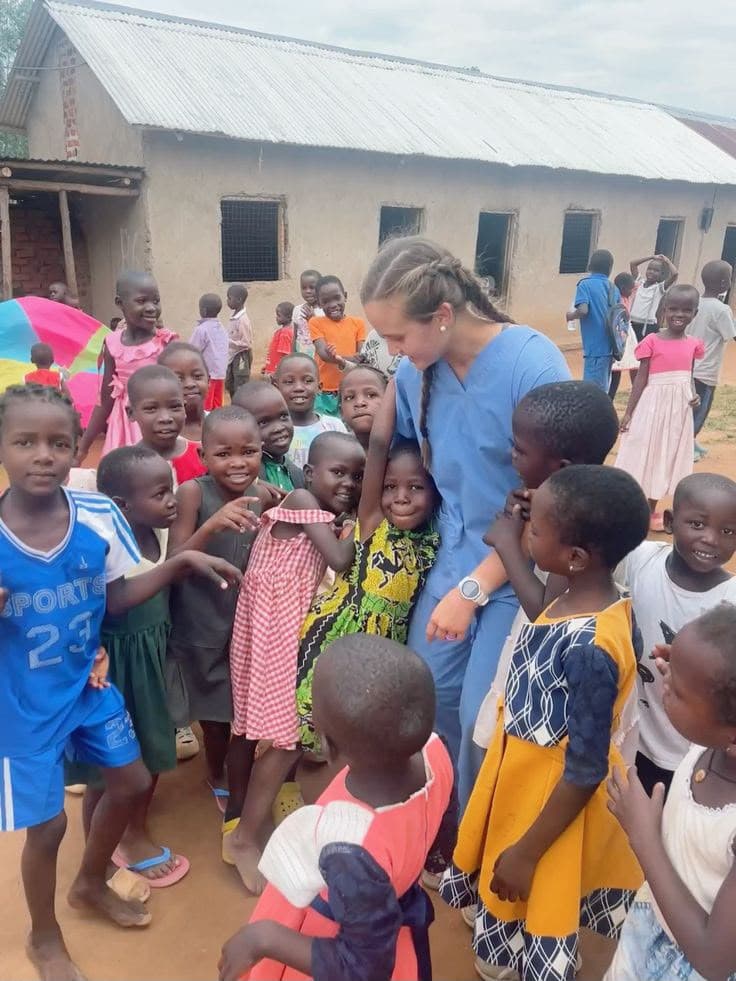 A volunteer surrounded by smiling children outside the home